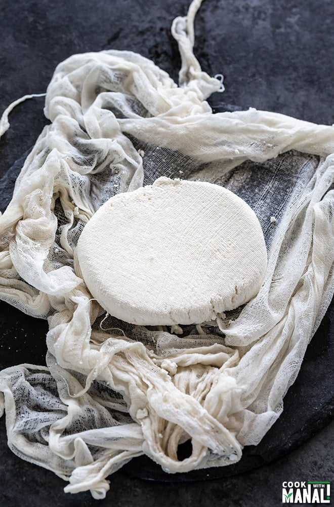 slab of homemade paneer placed in a muslin cloth