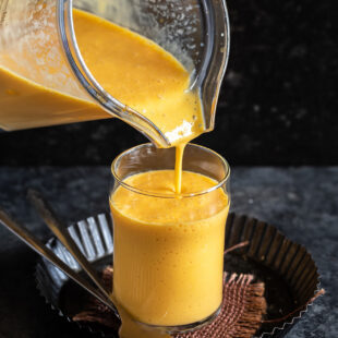 mango milkshake being poured into a glass from a blender