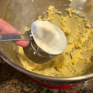 yogurt being added to a bowl with butter and sugar