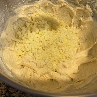 crumbled mawa being added to cake batter