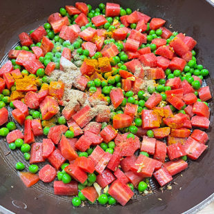 spices and salt added to carrot and green peas stir-fry