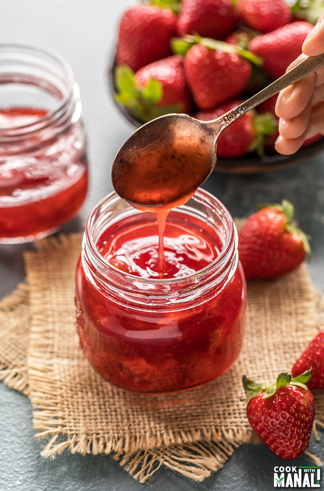 strawberry syrup in a jar with strawberries in the background