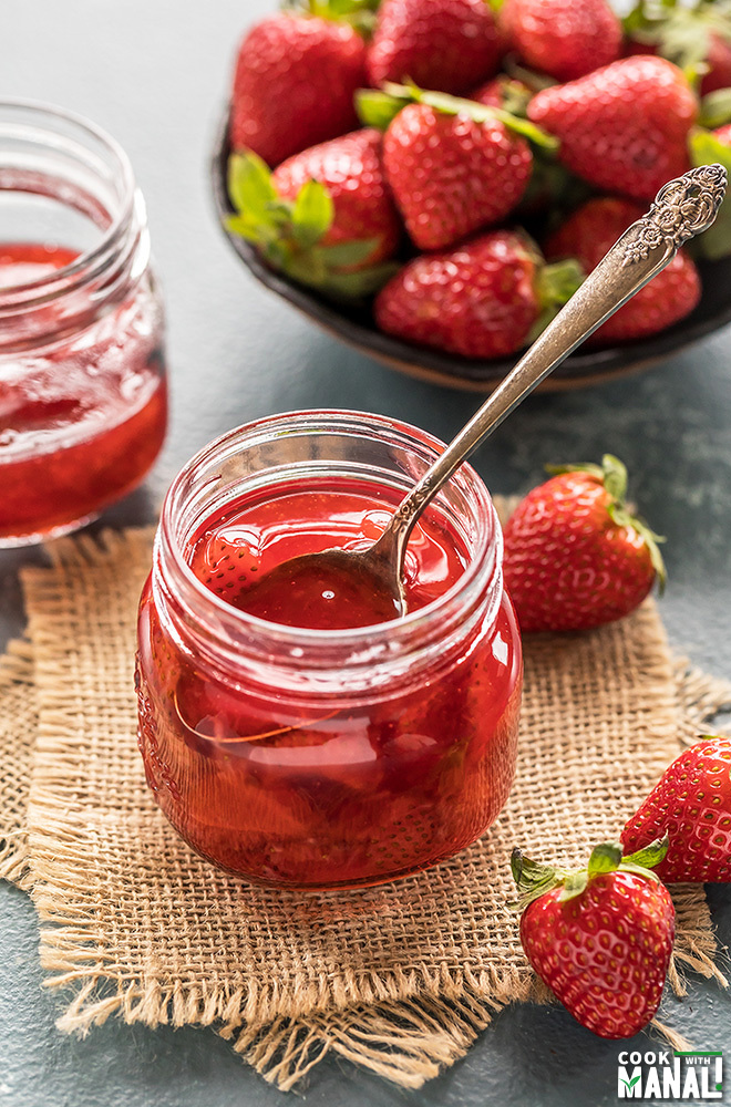 homemade strawberry syrup in a jar with a spoon