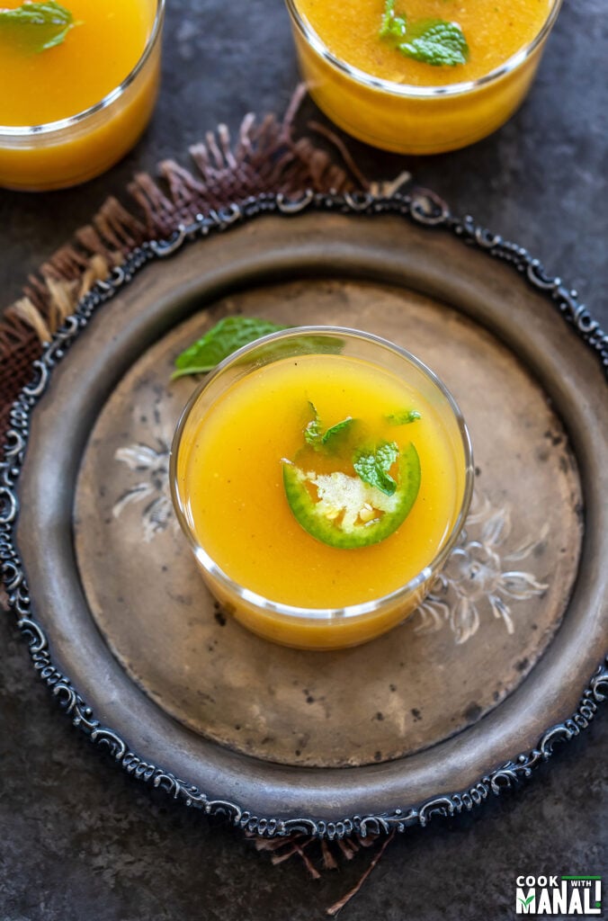 yellow color drink served in a glass garnished with mint and jalapeño