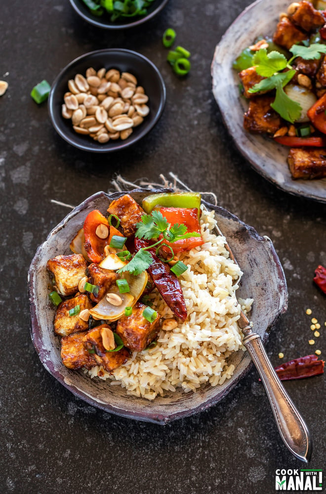 plate with brown rice and kung pao tofu and another plate of kung pao tofu on the side