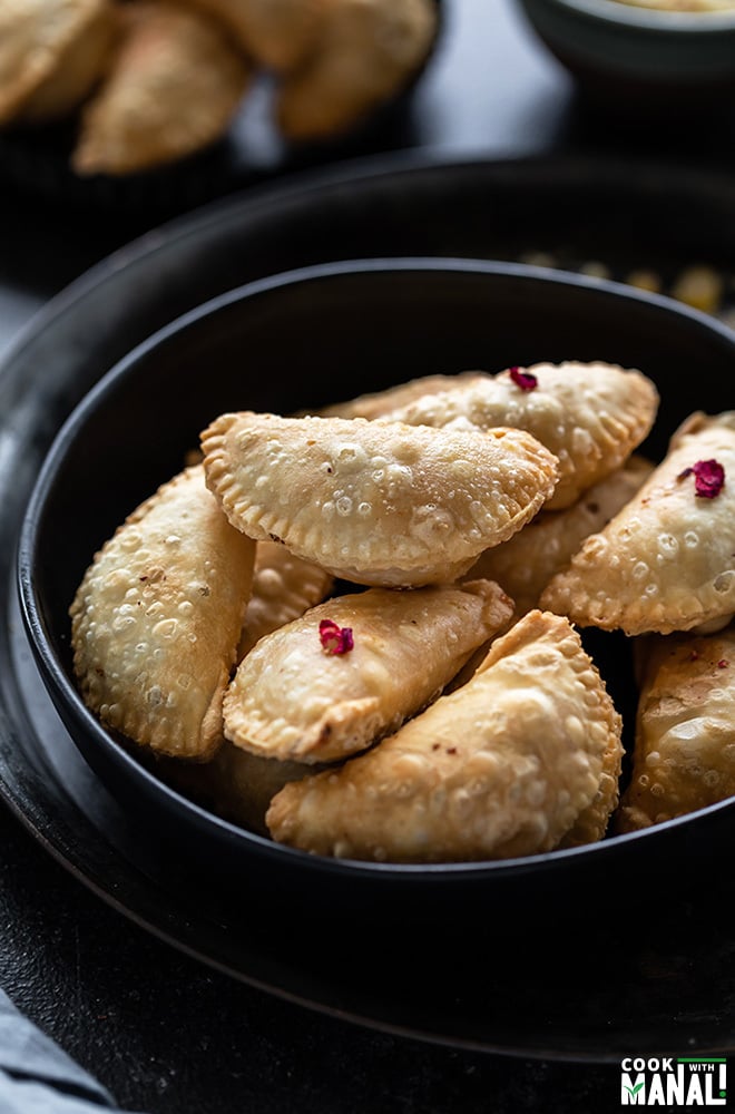 bowl of mawa gujiya with more gujiya in the background