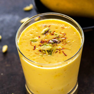 glass of mango lassi garnished with saffron and pistachios