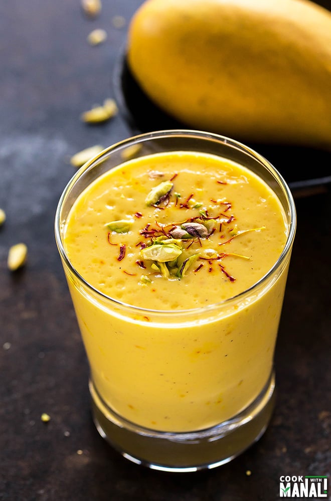 glass of mango lassi garnished with saffron and pistachios
