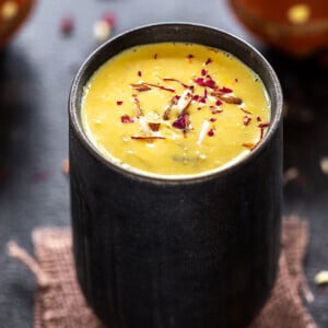 badam milk served in a black glass and garnished with saffron