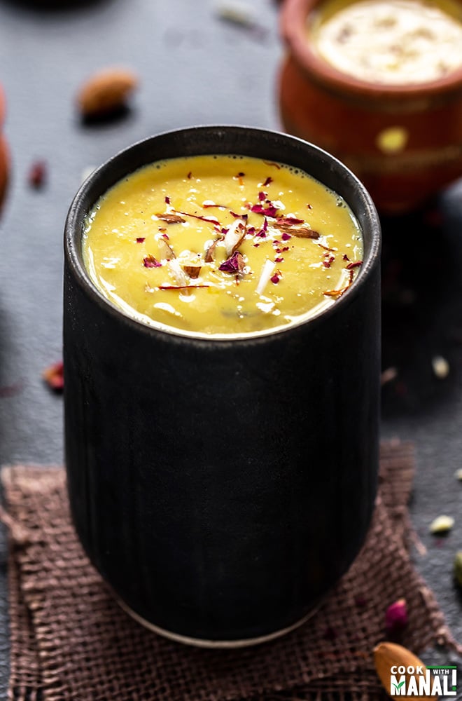 badam milk served in a black glass and garnished with saffron