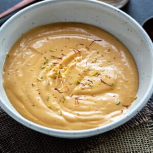 mango yogurt served in a white bowl garnished with saffron