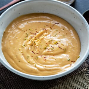 mango yogurt served in a white bowl garnished with saffron