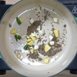 garlic, ginger, chili, cumin seeds being sautéed in a pan