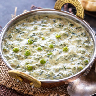 a white color curry with green peas and fresh fenugreek leaves served in a copper kadai