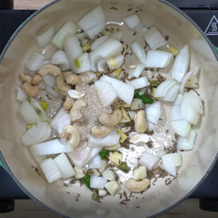 chopped onion, cashews, spices in a pan