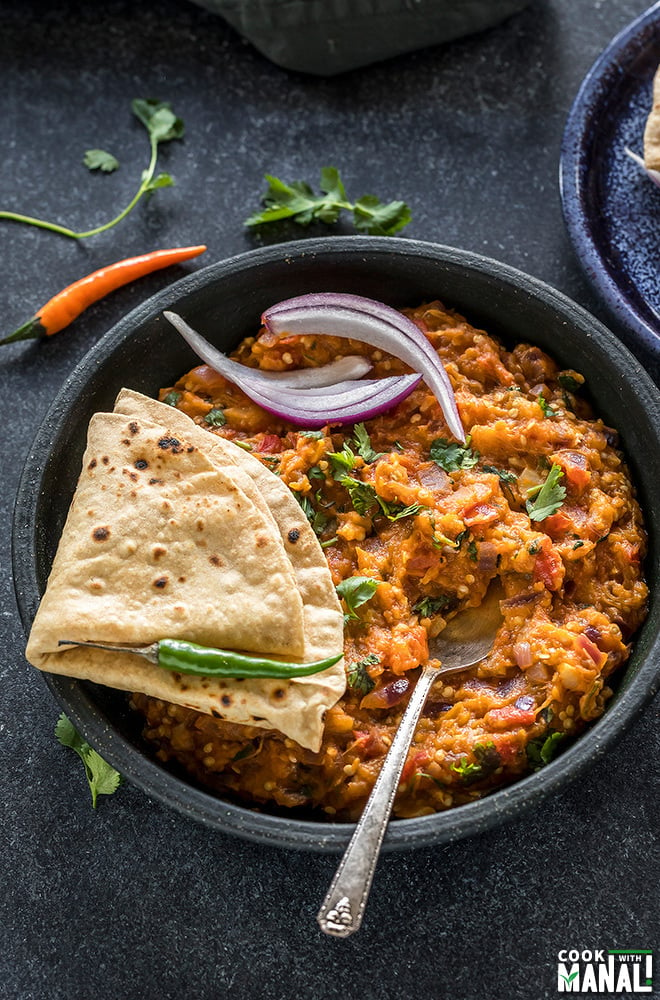 punjabi baingan bharta served in a black bowl with rotis on the side