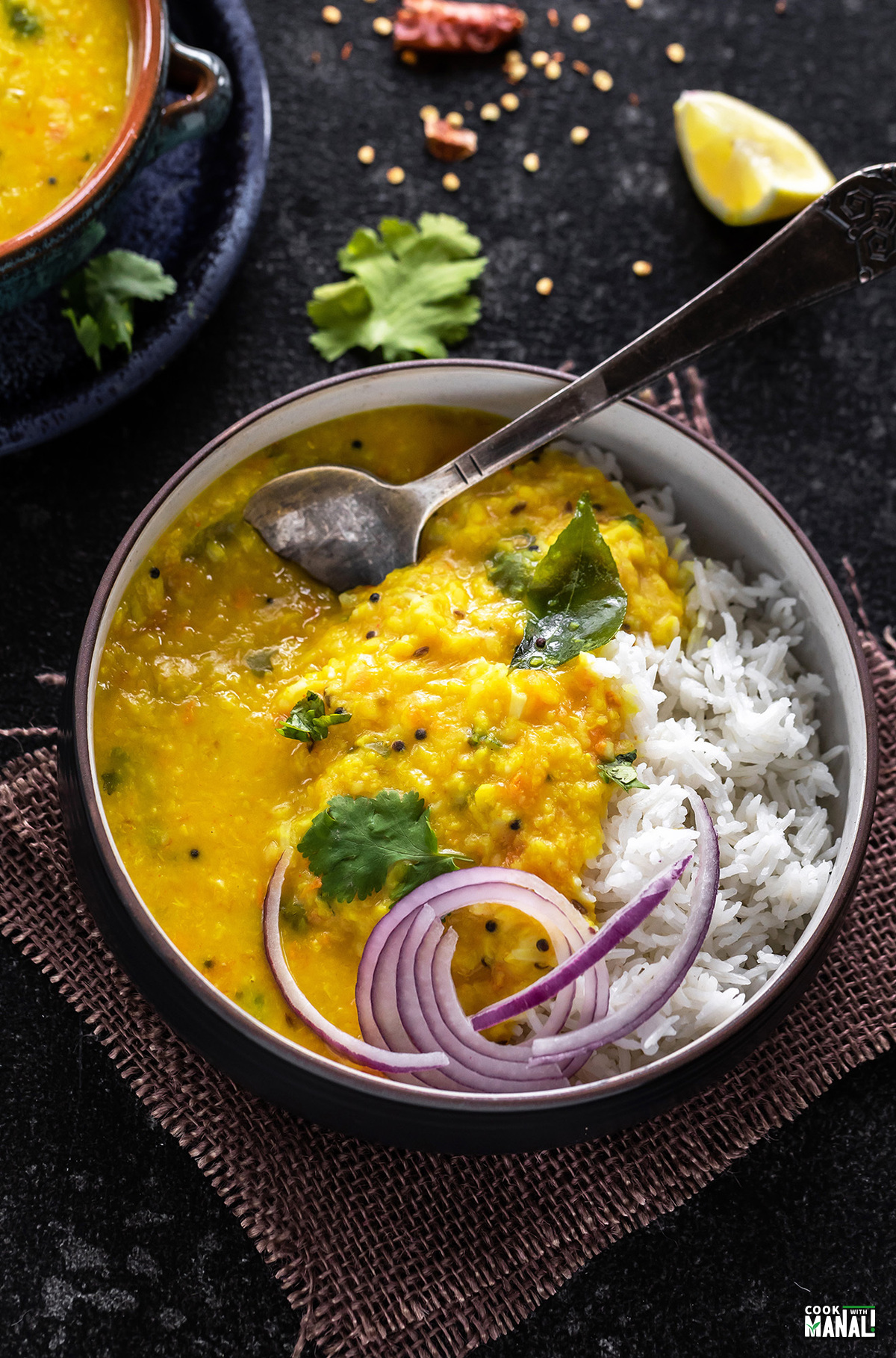 bowl of moong dal tadka and rice served with sliced onions