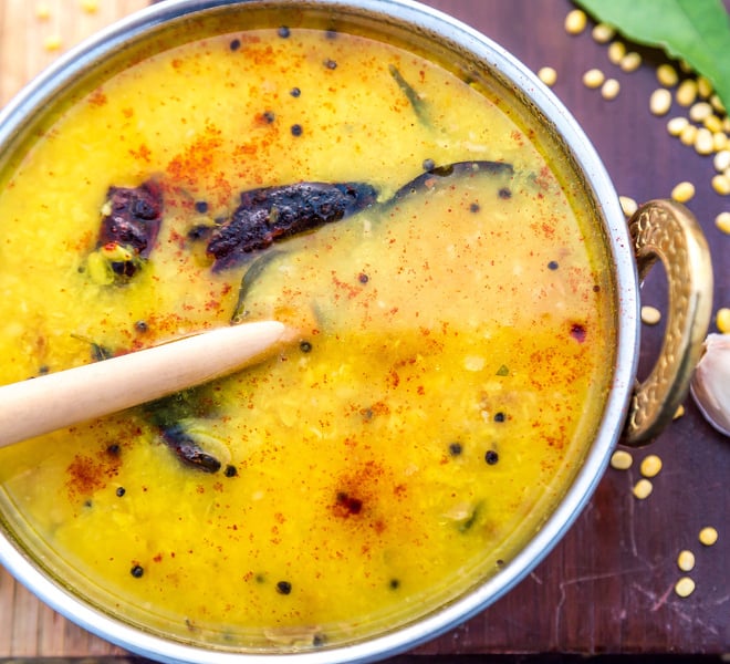 moong dal in a copper kadai with a spoon