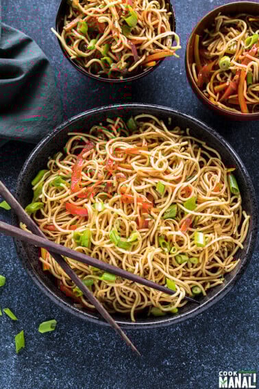 hakka noodles in a black bowl with a pair of chopsticks