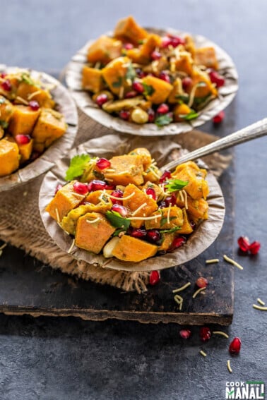 three bowls of sweet potato chaat topped with pomegranate, cilantro and sev