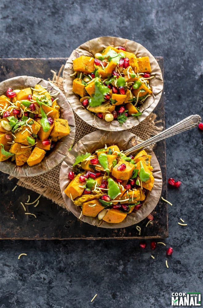 overhead shot of three bowl of sweet potato chaat arranged on a board