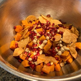 bowl with diced sweet potatoes, peanuts, pomegranate seeds