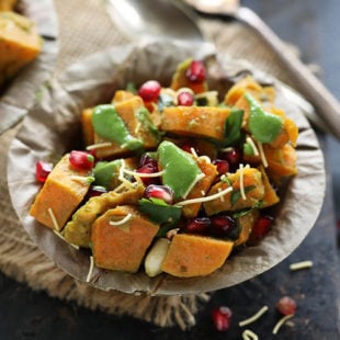 bowl of diced sweet potatoes topped with chutney, pomegranate seeds, cilantro