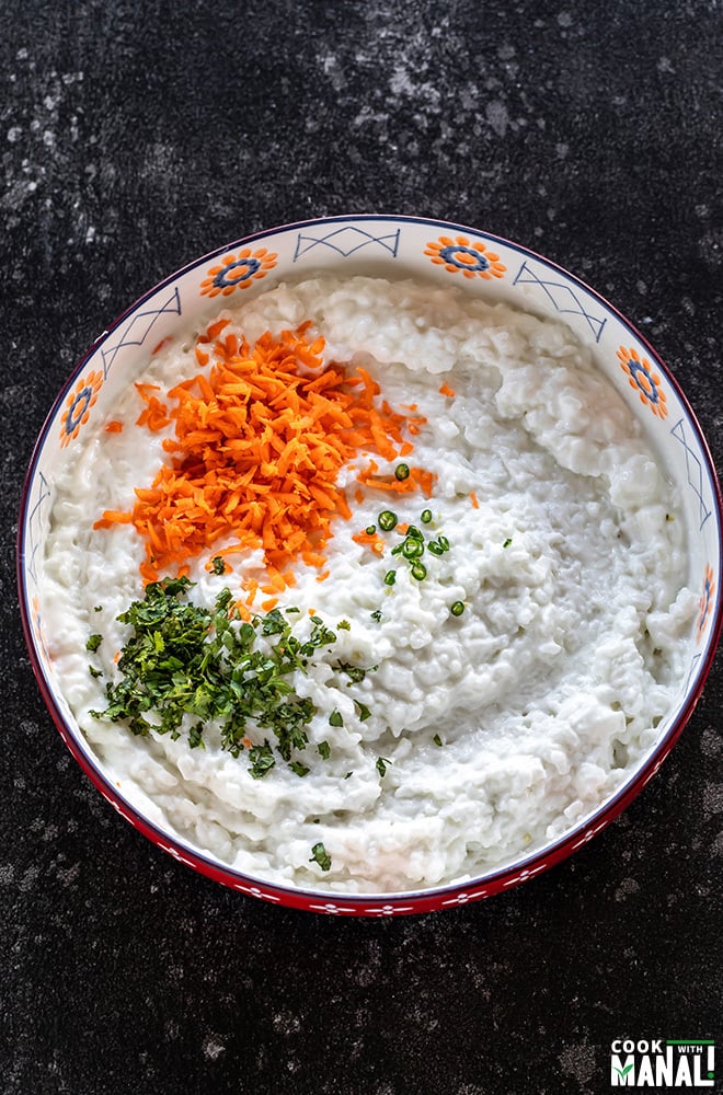 a large bowl with cooked rice mixed with yogurt and grated carrots, cilantro and green chilies