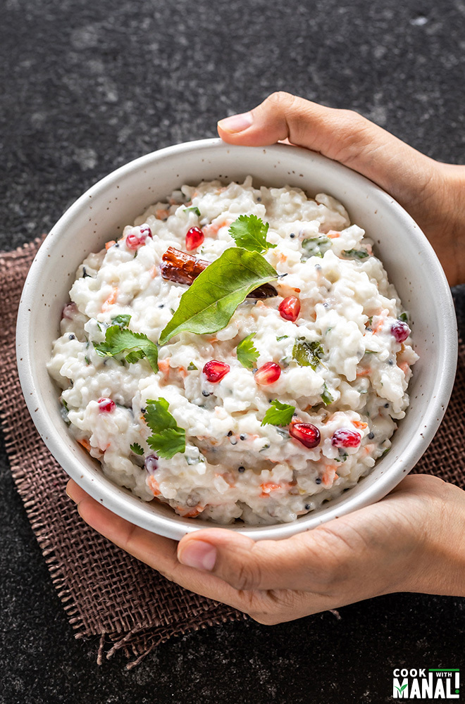 a pair of hand holding a bowl of curd rice