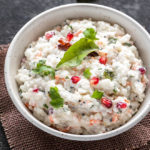 south indian style curd rice in a white bowl garnished with pomegranate arils