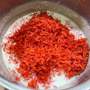 grated carrots added to a pot of milk
