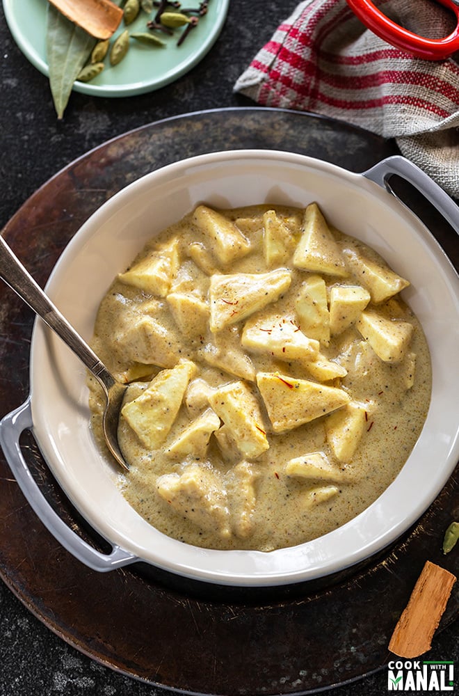 shahi paneer served in a small wok with spoon and a small plate of spices in the background