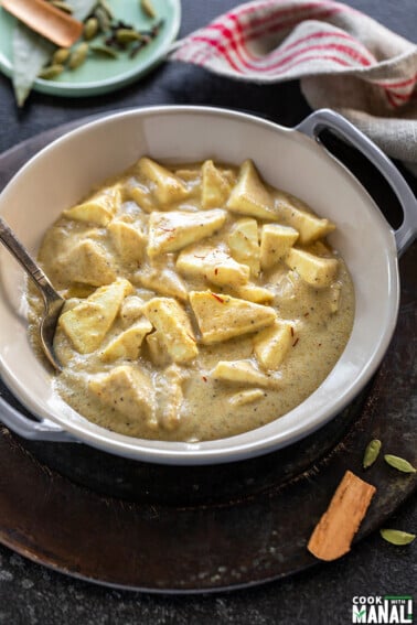 shahi paneer served in a small wok with spoon and a small plate of spices in the background