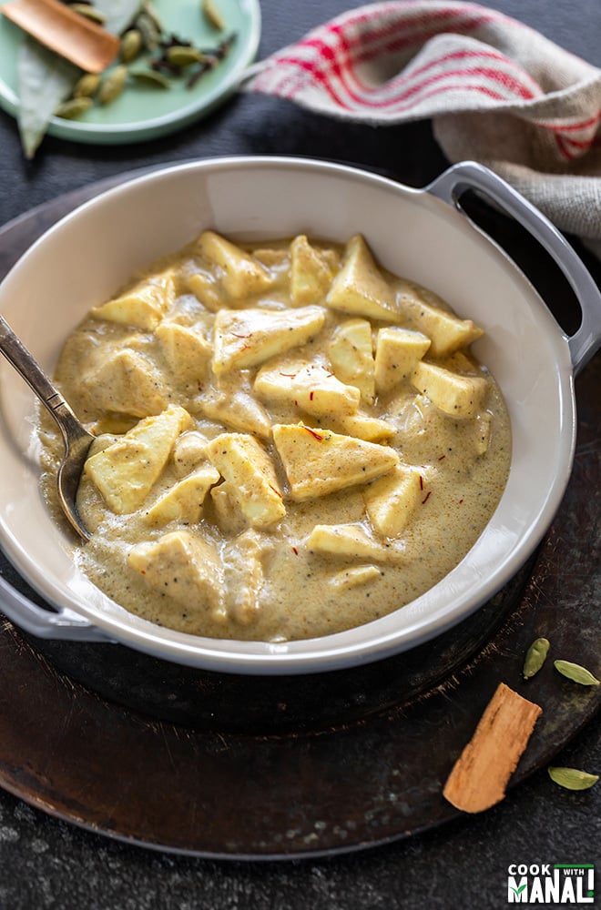 shahi paneer served in a small wok with spoon and a small plate of spices in the background