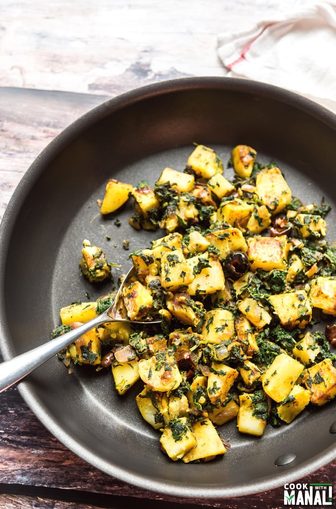 aloo palak in a pan with a spoon