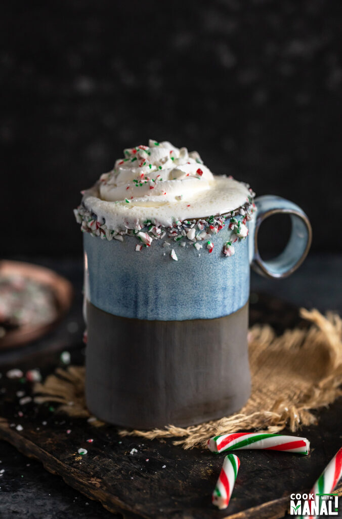 white hot chocolate served in a blue mug topped with whipped cream and crushed candy cane