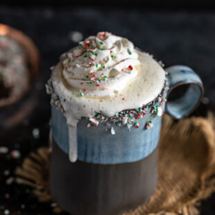 white hot chocolate dripping from the sides of the mug and topped with crushed candy cane