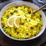 lemon rice served in a white bowl with two lemon sliced place on top