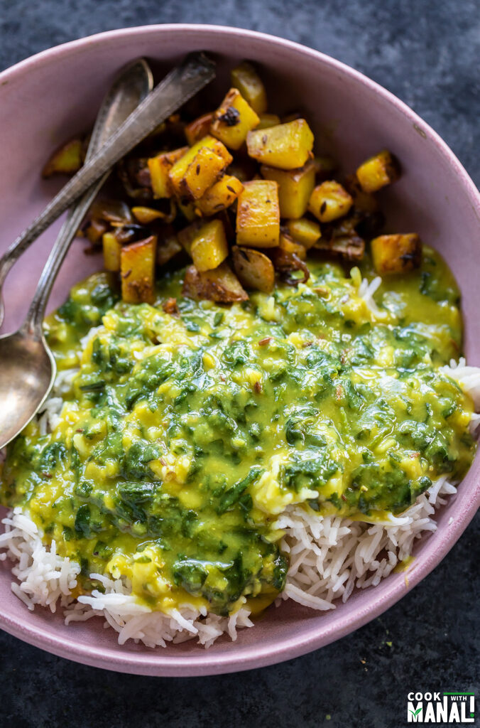 dal palak served with rice and aloo sabzi in a pink color bowl