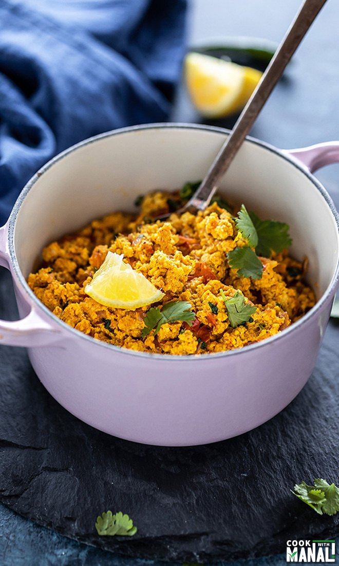 paneer bhurji served in a small pink pan and garnished with cilantro and lemon wedge