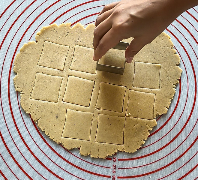 cookie dough cut into square shapes using a cutter