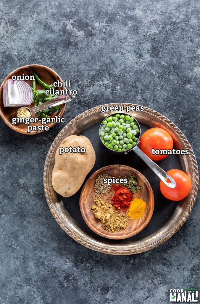 ingredients for aloo matar arranged in plates and placed over a board