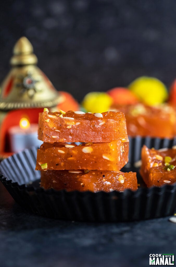 3 pieces of karachi halwa stacked together with tealights in the background