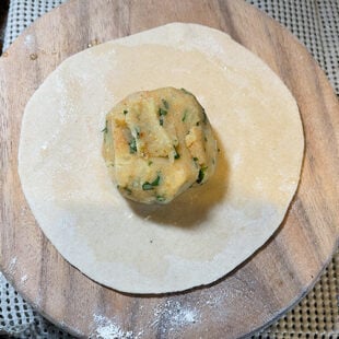spiced potato ball placed in middle of a rolled dough