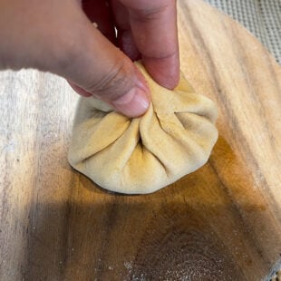 hand pinching a rolled dough to seal it