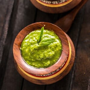 bowl of pesto garnished with a fresh basil leaf