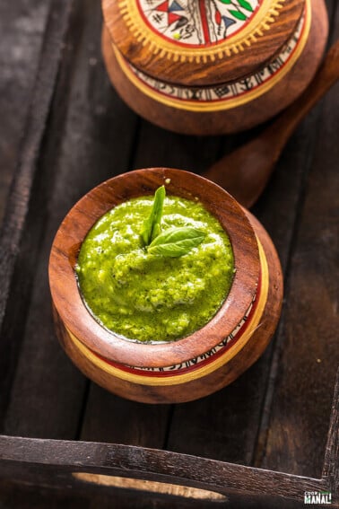 bowl of pesto garnished with a fresh basil leaf