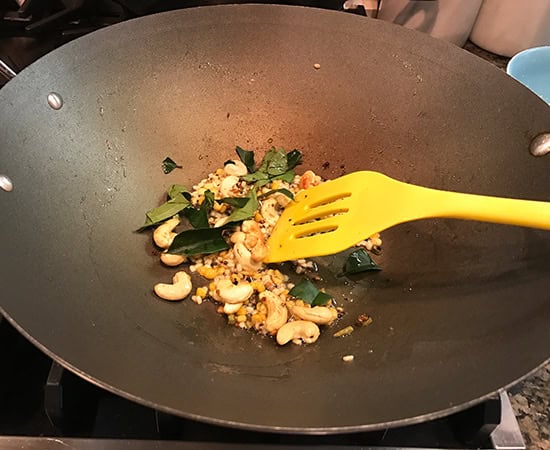 cashews curry leaves being cooked in a wok