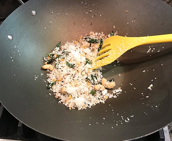coconut with spices being sauteed in a wok