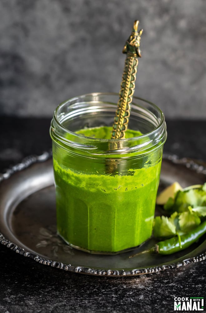 cilantro chutney served in a glass jar with a golden spoon